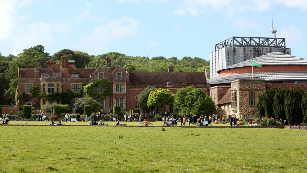 a large building both old and new in the background of a large green lawn