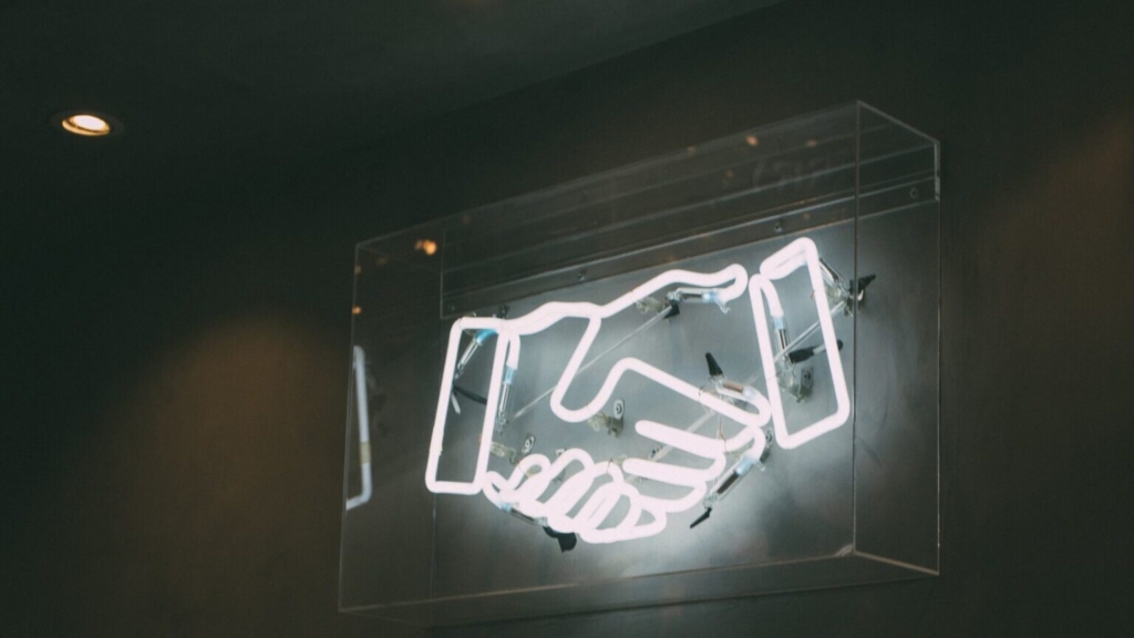 a neon light in the shape of a handshake