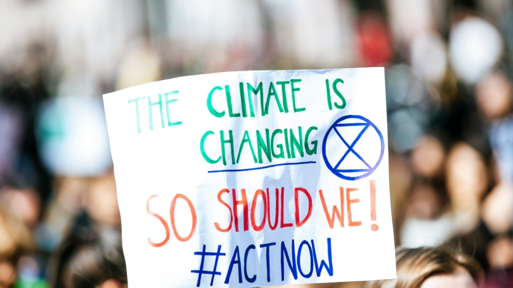 a white protest sign with the words the climate is changing, so should we! #ActNow