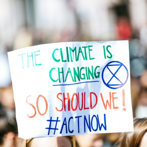 a white protest sign with the words the climate is changing, so should we! #ActNow