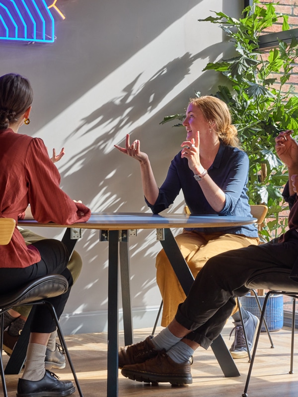 four people sit at a table, they look to be in deep thought and discussion